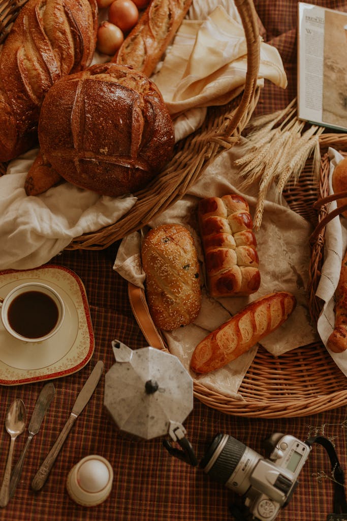 Warm rustic setting with fresh bread, a cup of coffee, and a camera on a checkered tablecloth.