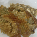 A serving of baked casserole with a golden-brown, crispy topping and a moist, textured interior on a white plate.